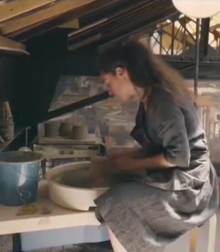 Créatrice de Cimer la Poterie en train de façonner une pièce en argile au tour de potier, dans son atelier lumineux.